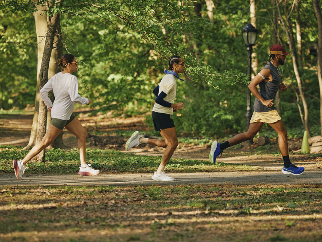 Kolme miestä juoksee metsässä